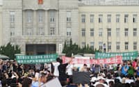 14日、中国・大連市の市政府庁舎前で化学工場の撤去を求め抗議する市民ら=共同