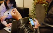 スマートフォンで自らを撮影し、インターネット中継で有権者と対話する立候補者(右)（25日、東京都渋谷区）