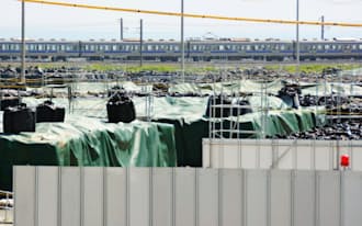 除染で出た放射性廃棄物の仮置き場脇を走るJR常磐線の列車（1日、福島県楢葉町）