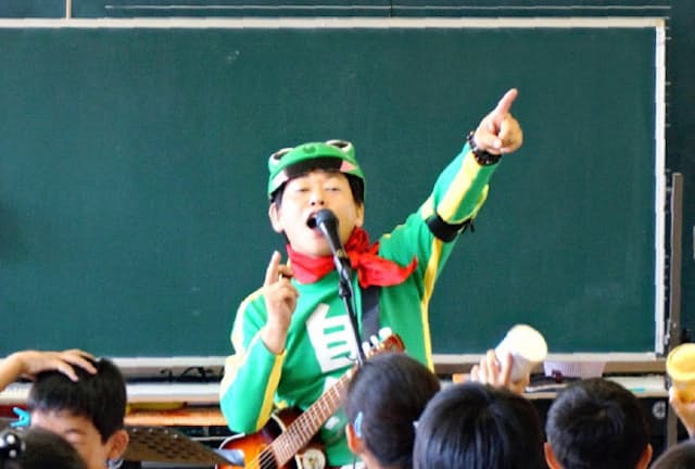 小学校の音楽室で自作のエコ楽曲を歌う平田彰宏さん