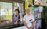 切符売り場の隣に理髪店の入り口がある。塚本久夫さん(右)と朝子さん夫妻