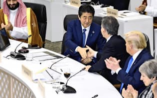G20大阪サミットで「大阪首脳宣言」を採択し、出席者と握手する安倍首相=手前左から2人目（6月29日、大阪市）=共同