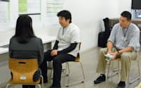 指導者（右）が見守る中、模擬患者（左）の目を見ながら面接する高橋医師（11月、東京都豊島区）