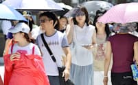 厳しい暑さとなった東京・銀座で、日傘やサングラスで強い日差しを避ける歩行者（13日）
