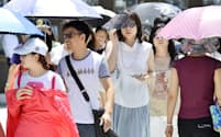 厳しい暑さとなった東京・銀座で、日傘やサングラスで強い日差しを避ける歩行者（13日）
