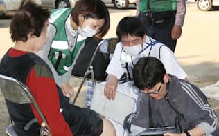避難所の被災者にエコノミークラス症候群の診断をする熊本市民病院の医療チーム（19日、熊本県益城町）
