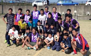 避難所で子どもたちとサッカー交流し、記念写真に納まるJ2熊本の巻誠一郎（前列左から4人目）ら=Jリーグ提供