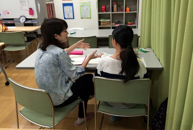 居場所に通う子ども（右）に勉強を教えるボランティア（東京都足立区）