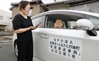 配車依頼するウーバーのアプリが入った端末を持つ女性(左)と「ささえ合い交通」の自家用車（京都府京丹後市）