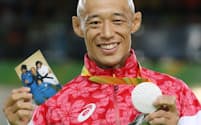 柔道男子60キロ級で銀メダルを獲得し家族の写真を手に笑顔の広瀬誠=寺沢将幸撮影
