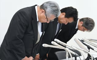 記者会見で頭をさげる電通の中本副社長執行役員(左)ら（23日午後、東京都中央区）