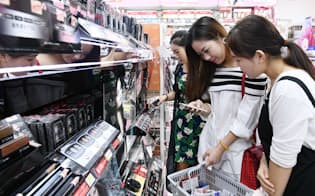 スマホを店員(右)に見せて商品を探す訪日客(東京都台東区のマツモトキヨシ浅草二天門前店)