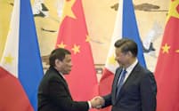 握手するフィリピンのドゥテルテ大統領(左)と中国の習近平国家主席（20日、北京の人民大会堂）=共同