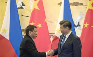 調印式で握手するフィリピンのドゥテルテ大統領(左)と中国の習近平国家主席（20日、北京の人民大会堂）=共同