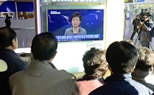 国民向け談話を発表する韓国の朴槿恵大統領のテレビ画像を見る市民ら（29日、ソウル）=共同