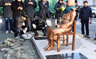 韓国・釜山の日本総領事館前の歩道に、従軍慰安婦被害を象徴する少女像を設置する市民団体のメンバーら（12月30日）=共同