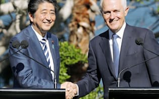 　共同記者発表を終え、オーストラリアのターンブル首相（右）と握手する安倍首相=14日、シドニー（共同）