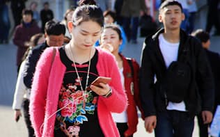 繁華街で携帯を見る女性（北京）