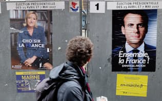 投票所近くに掲げられた中道マクロン氏（右）と極右ルペン氏のポスター（6日、パリ）=浅原敬一郎撮影