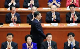 党の活動報告を終え拍手の中、席に戻る習近平総書記（18日、北京の人民大会堂）=小高顕撮影