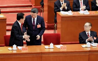 胡錦濤・前国家主席(左)に先に握手を求める習近平氏を見つめる江沢民・元国家主席(右)（18日、北京）=小高顕撮影

