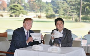 ゴルフ場での昼食前に、サインした帽子を見せる安倍首相とトランプ米大統領（5日午後、埼玉県川越市の霞ケ関カンツリー倶楽部）=代表撮影