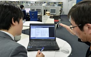 講師(右)の指導のもと、ソフトを使い経済予測に挑戦する記者（東京都千代田区の日本経済研究センター）