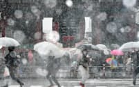 雪が降るなか浅草寺の雷門前を歩く人たち（22日午後、東京都台東区）
