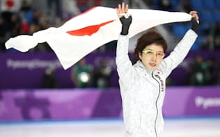 スピードスケート女子1000メートルで銀メダルを獲得し日の丸を掲げる小平選手（14日、江陵）=上間孝司撮影