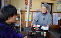 特産のカキを使った菓子を提供する藤井サヱ子さん(右)（2月26日、岩手県釜石市）