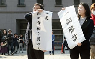 京都地裁前で「一部勝訴」と書かれた垂れ幕を掲げる原告側弁護士（15日午前）=共同