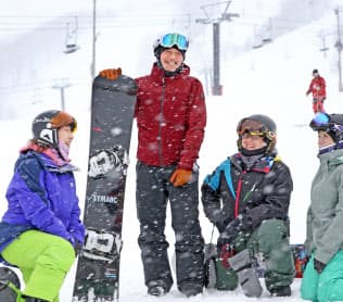障害者スノーボード滑走会の参加者と談笑する二星さん（左から２人目）＝２月12日、長野県小谷村