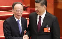 握手する国家主席に再選された習近平氏(右)と国家副主席に選出された王岐山氏（17日、北京の人民大会堂）=三村幸作撮影