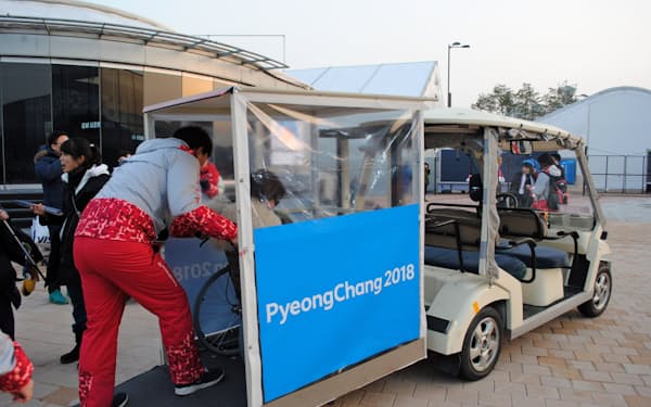 会場内でゴルフカートを改造した乗り物に乗り込む車いすの女性(江陵)=西城彰子撮影