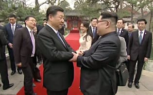 中国中央テレビが28日放映した、北京の釣魚台迎賓館で握手する中国の習近平国家主席（左）と北朝鮮の金正恩朝鮮労働党委員長の映像=共同