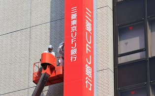 「三菱UFJ銀行」に名称を変更して看板の掛け替えをする作業員（1日午前、東京都千代田区）
