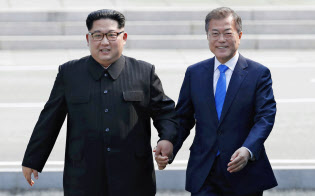 南北首脳会談で韓国の文在寅(ムン・ジェイン)大統領(右)と軍事境界線を越える北朝鮮の金正恩(キム・ジョンウン)委員長(4月27日、板門店)=韓国共同写真記者団・共同 南北首脳会談で韓国の文在寅(ムン・ジェイン)大統領(右)と軍事境界線を越える北朝鮮の金正恩(キム・ジョンウン)委員長(4月27日、板門店)=韓国共同写真記者団・共同