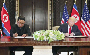 合意文書に署名する北朝鮮の金正恩委員長(左)とトランプ米大統領(12日、シンガポール)=ロイター 合意文書に署名する北朝鮮の金正恩委員長(左)とトランプ米大統領(12日、シンガポール)=ロイター