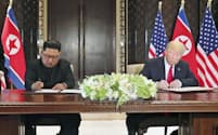合意文書に署名する北朝鮮の金正恩委員長（左）とトランプ米大統領（12日、シンガポール）=ロイター