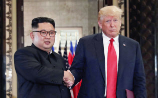 合意文書を交換し、握手する北朝鮮の金正恩委員長(左)とトランプ米大統領(12日、シンガポール)=ロイター 合意文書を交換し、握手する北朝鮮の金正恩委員長(左)とトランプ米大統領(12日、シンガポール)=ロイター