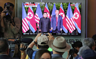 12日、米朝首脳会談の模様を伝えるテレビ画面を見るソウルの人々=AP 12日、米朝首脳会談の模様を伝えるテレビ画面を見るソウルの人々=AP