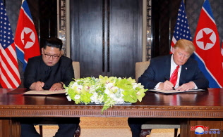米朝首脳会談後、共同声明に署名する金正恩委員長(左)とトランプ大統領(6月12日、シンガポール)=ロイター 米朝首脳会談後、共同声明に署名する金正恩委員長(左)とトランプ大統領(6月12日、シンガポール)=ロイター