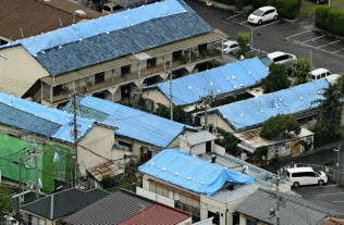 地震で被災し、屋根がブルーシートで覆われた建物(19日午後、大阪府高槻市)=共同 地震で被災し、屋根がブルーシートで覆われた建物(19日午後、大阪府高槻市)=共同