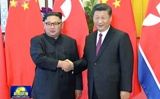 中国中央テレビが19日放映した、北京で握手する北朝鮮の金正恩朝鮮労働党委員長(左)と中国の習近平国家主席の映像=共同 中国中央テレビが19日放映した、北京で握手する北朝鮮の金正恩朝鮮労働党委員長(左)と中国の習近平国家主席の映像=共同