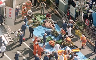 1995年3月、地下鉄サリン事件で、日比谷線「築地駅」前の路上で手当てを受ける被害者=共同