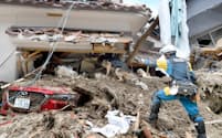 土砂崩れにより倒壊した家屋で警備犬を使って行方不明者を捜索する機動隊員（9日午前、広島市安芸区）