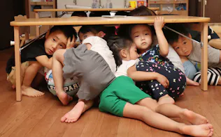 避難訓練で机の下に入って頭を守る「中崎町かいせい保育園」の園児(大阪市北区)