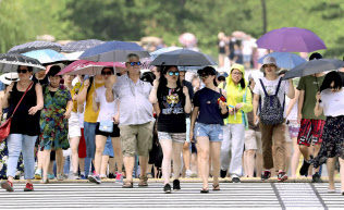 厳しい暑さの中、日傘を差して歩く外国人観光客ら(24日午前、東京都千代田区)=共同 厳しい暑さの中、日傘を差して歩く外国人観光客ら(24日午前、東京都千代田区)=共同