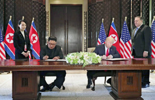米朝首脳会談後、共同声明に署名する北朝鮮の金正恩委員長(左)とトランプ米大統領(6月12日、シンガポール)=ロイター 米朝首脳会談後、共同声明に署名する北朝鮮の金正恩委員長(左)とトランプ米大統領(6月12日、シンガポール)=ロイター