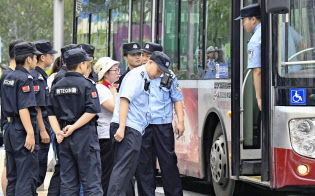大規模な陳情活動が計画された政府機関の周辺で、警察官に取り囲まれる女性(6日、北京)=共同 大規模な陳情活動が計画された政府機関の周辺で、警察官に取り囲まれる女性(6日、北京)=共同